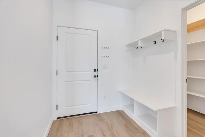 Dedicated mudroom area featuring a built-in bench, integrated storage cubbies, wall-mounted coat hooks, and additional wall hooks