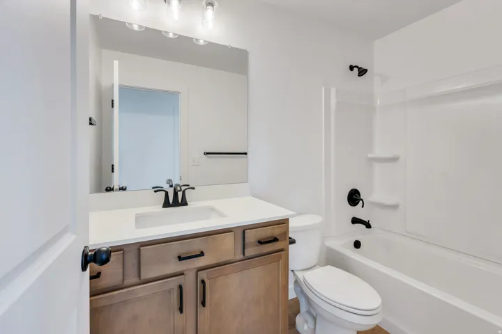 Bathroom featuring a wood-finish vanity with a light-toned countertop, an integrated sink, and a large wall-mounted mirror