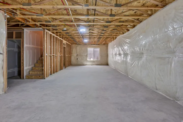 Unfinished basement with exposed ceiling joists and concrete flooring