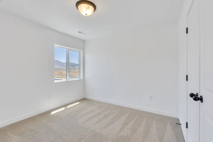 Bright room featuring light beige carpet flooring, white walls, a single window, and a flush mount ceiling light fixture