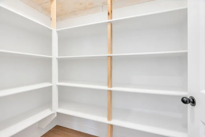 Corner pantry featuring extensive white shelving