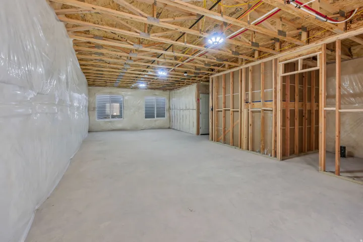 Unfinished basement featuring exposed wood ceiling joists and framing, concrete flooring, and multiple recessed light fixtures