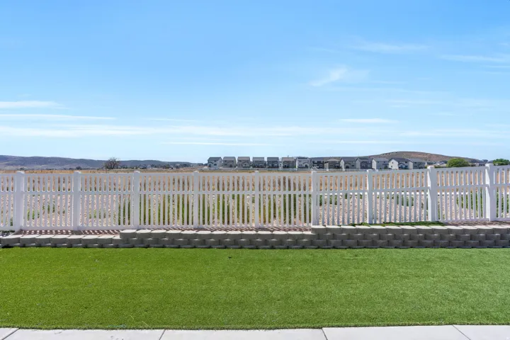 Manicured green lawn with a white picket fence and a retaining wall