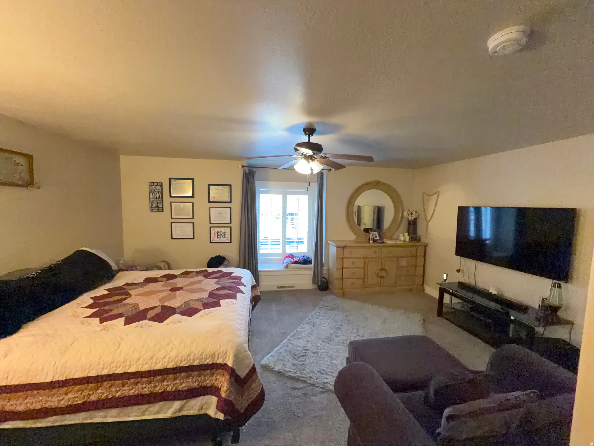 Spacious room featuring neutral-toned walls, a ceiling fan, and carpet flooring