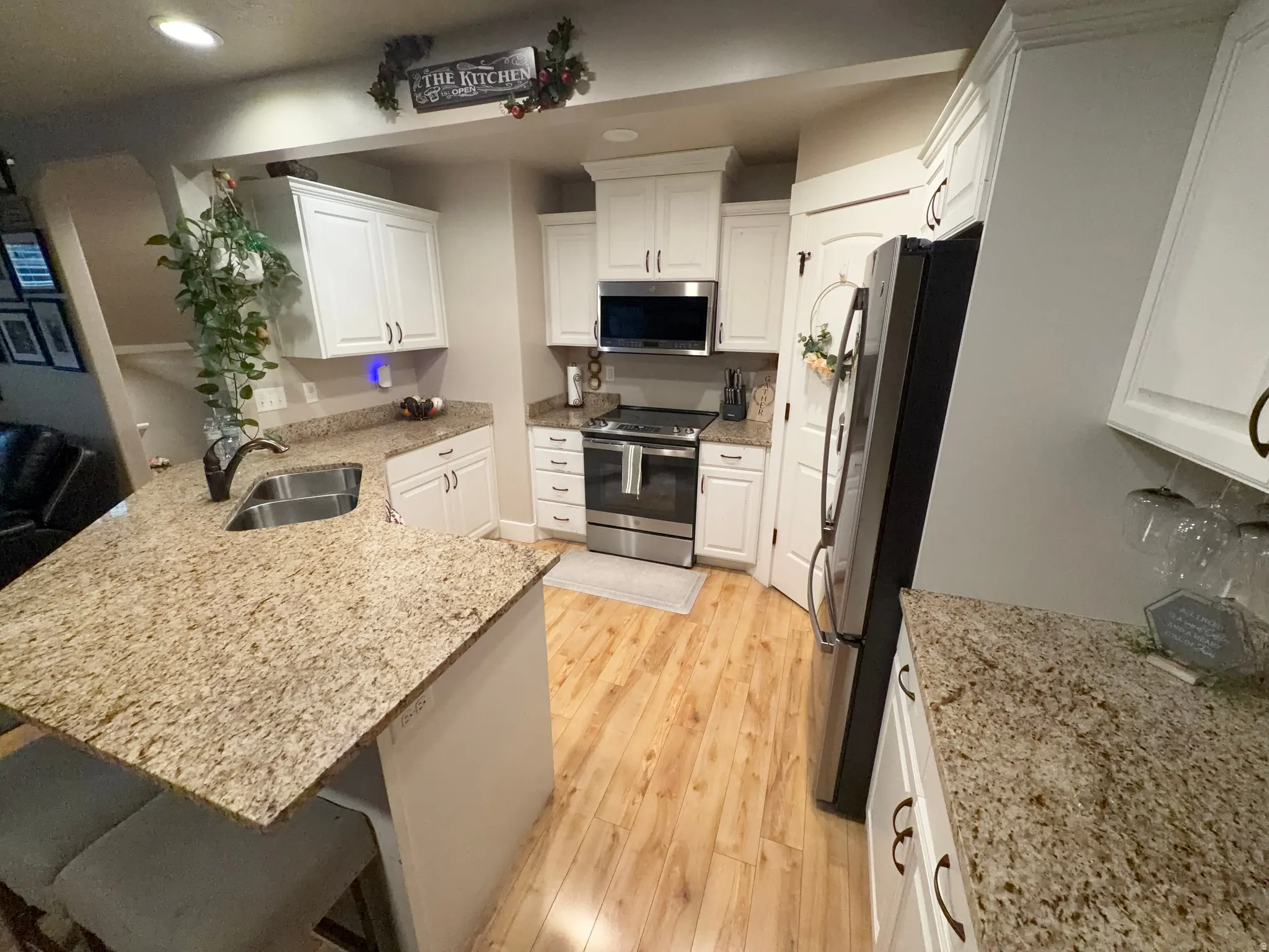 Kitchen featuring light wood-finish flooring, white cabinetry, and light-colored speckled countertops