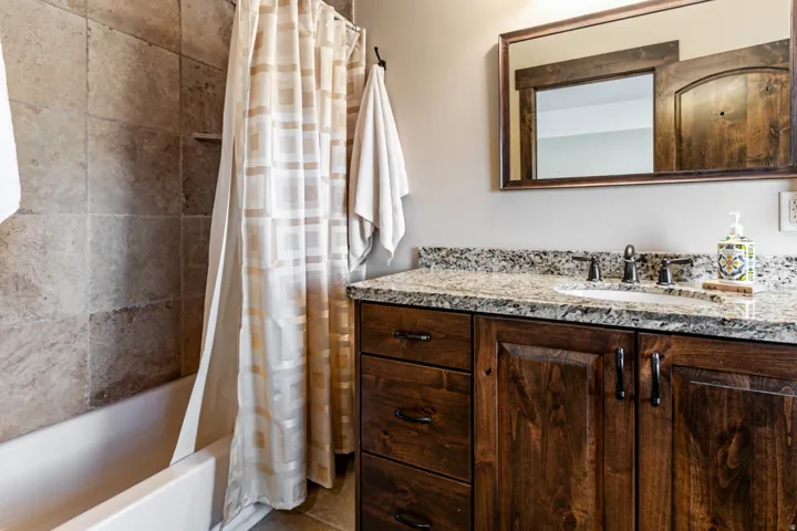 Bathroom vanity with a granite-style countertop, undermount sink, and dark wood cabinetry