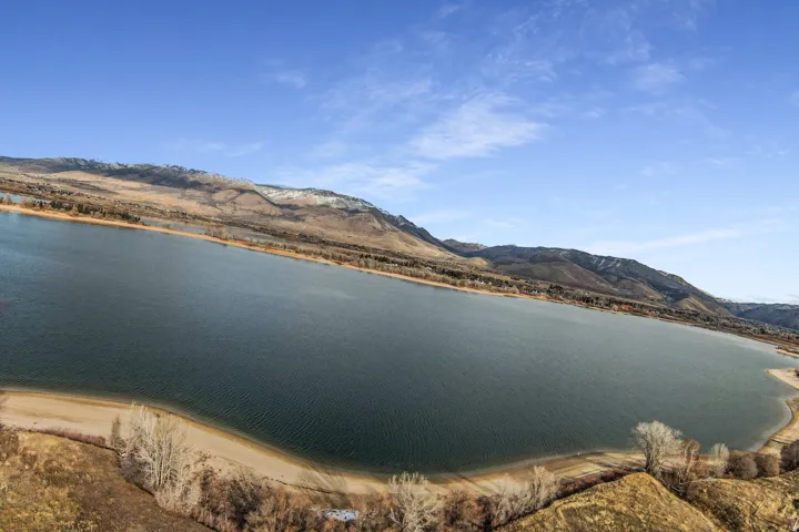 Expansive body of water bordered by a natural shoreline and distant mountains