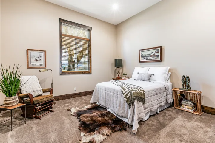 Neutral tone walls with wood trim, large window with blinds, and carpeted flooring