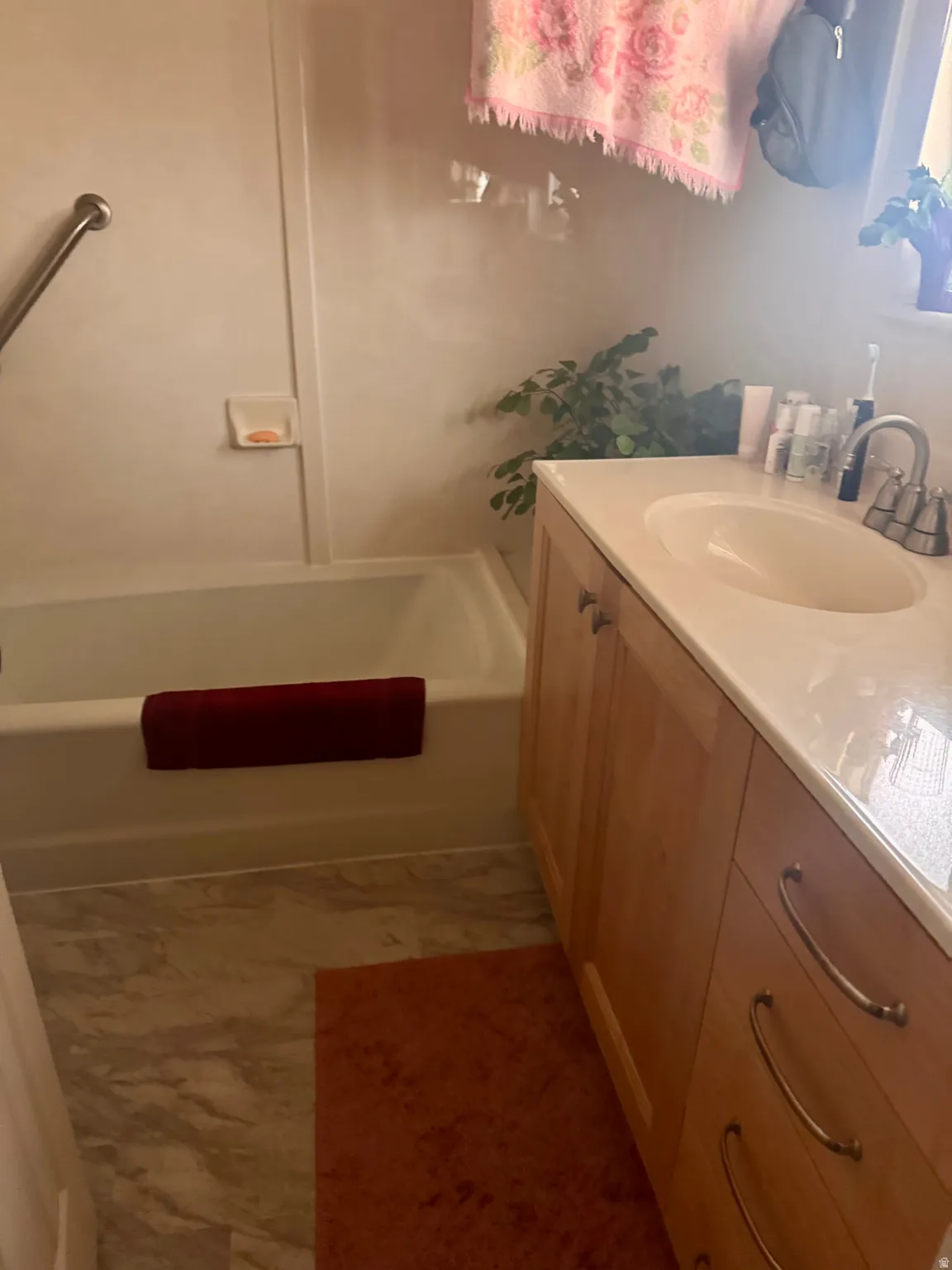 Bathroom featuring a full-size bathtub, light wood-finish vanity with a white countertop and integrated sink, and a chrome faucet