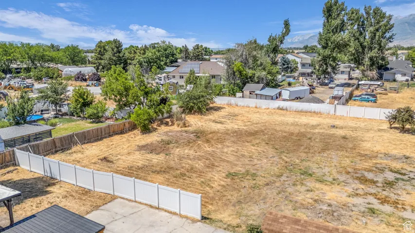 Expansive open lot with a large, level building area, featuring a white privacy fence along one boundary and a wood fence along another