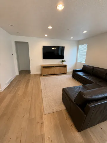 Bright living area featuring wood-finish flooring, recessed lighting, and a window with blinds