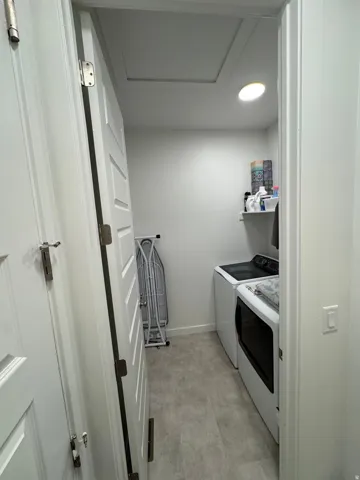 Dedicated laundry area featuring light-toned flooring, white walls, built-in shelving, and recessed lighting