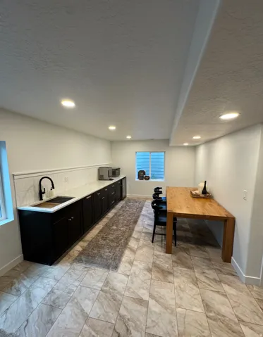 Kitchenette featuring black cabinetry, light-toned countertop, and a white subway tile backsplash