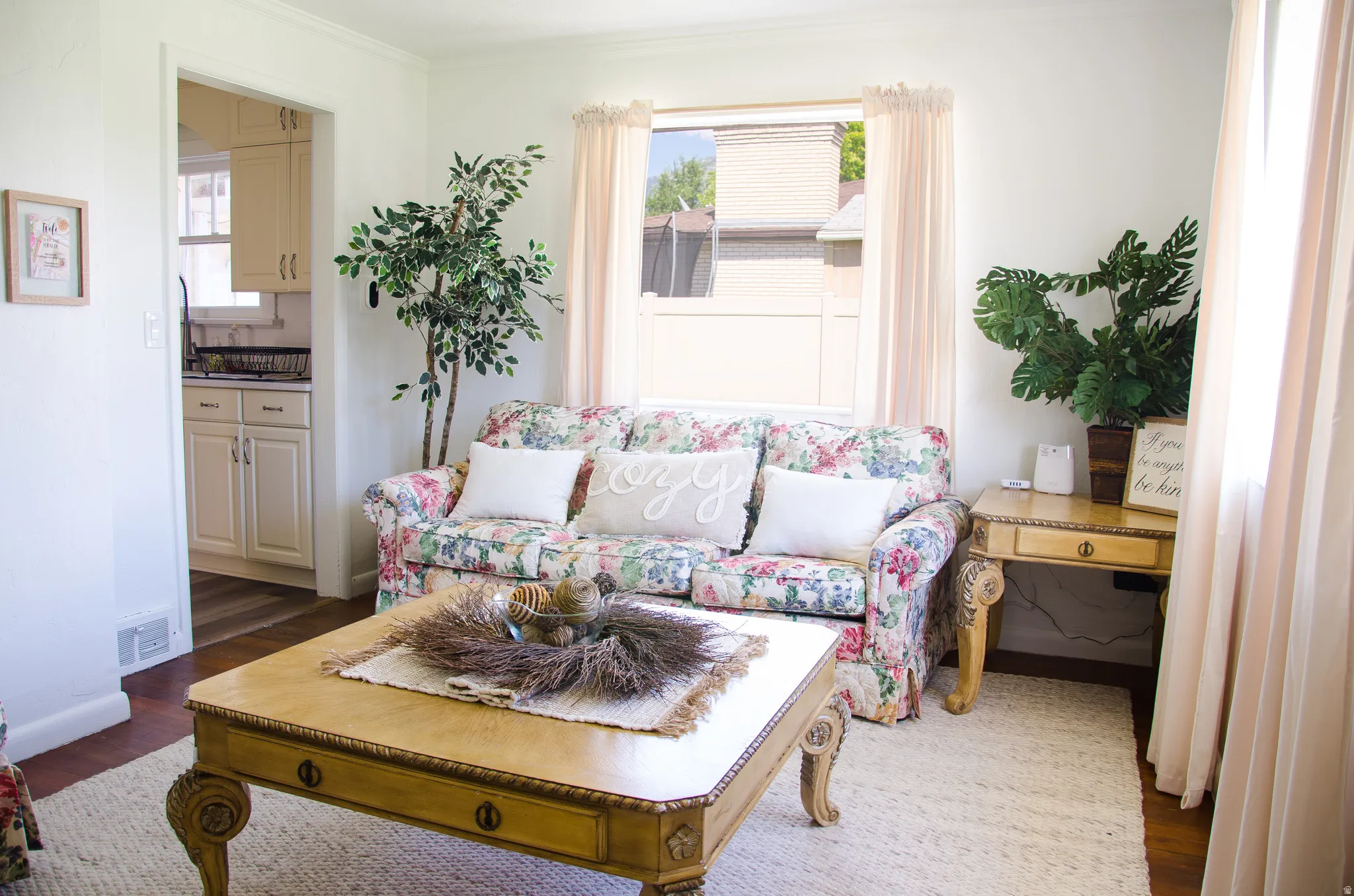 Living area featuring wood-finish flooring, white painted walls, and a large window with natural light