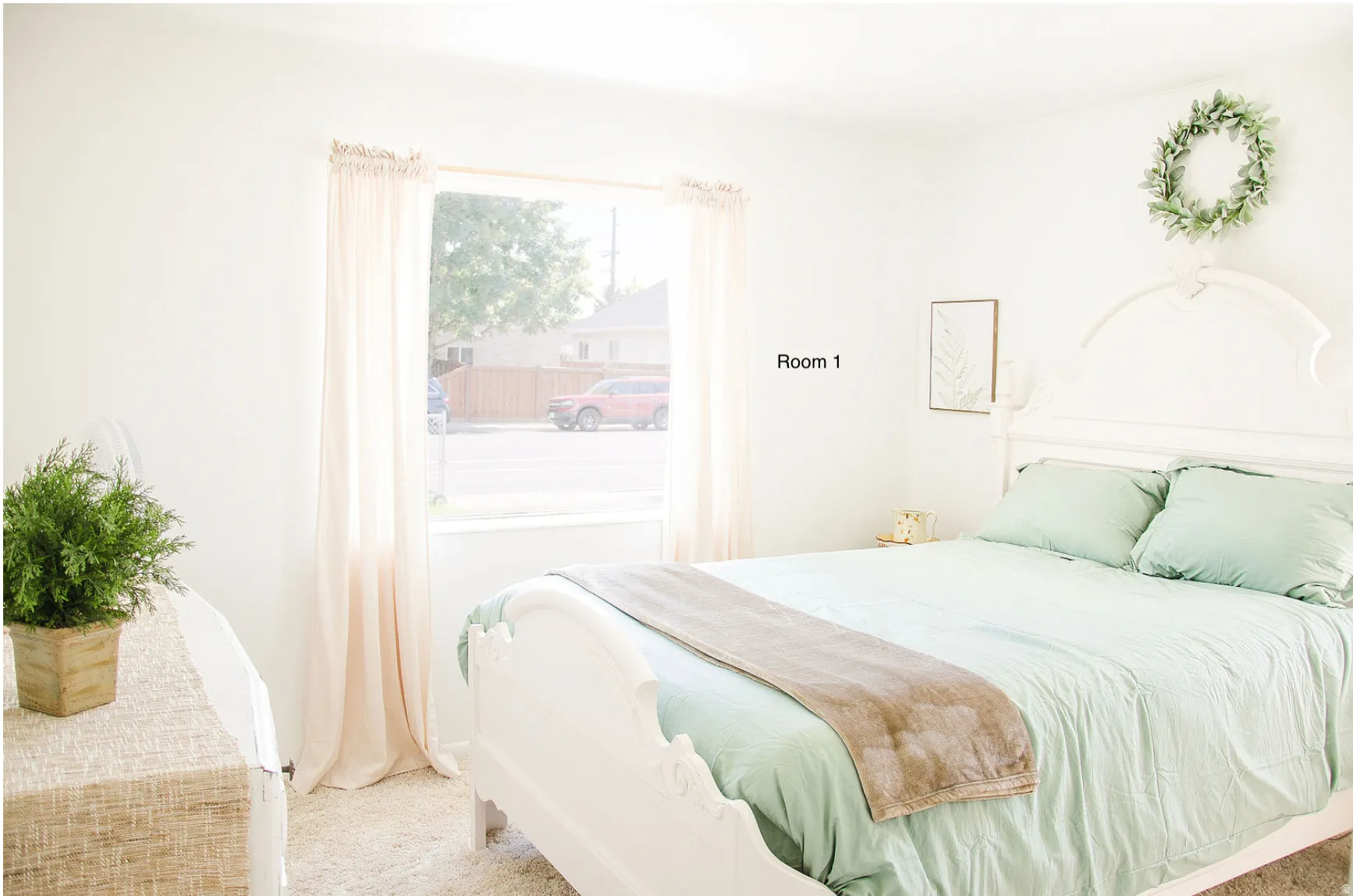 Bright interior room featuring a large window, white walls, and light-colored carpeting