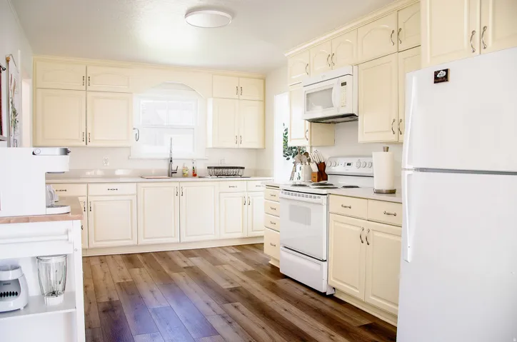 Kitchen featuring extensive cream cabinetry, wood-finish flooring, and white countertops