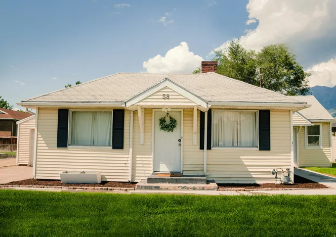 Single-story residence featuring light-colored siding, contrasting dark shutters, and a prominent front gable