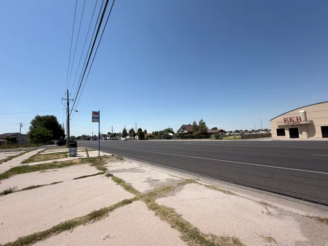 Paved road frontage with a commercial building visible in the background featuring a light-colored facade