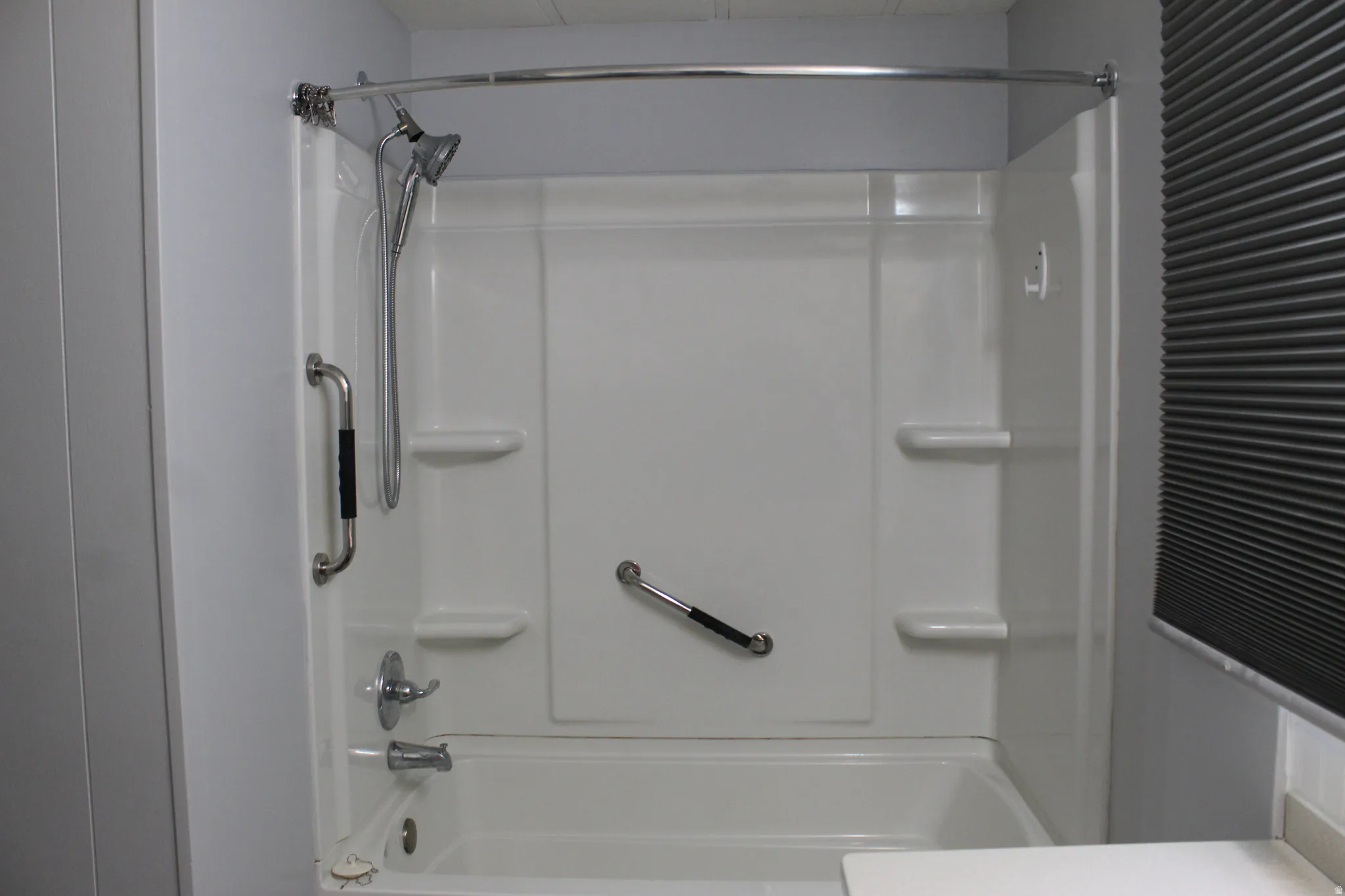 Primary bathroom White acrylic tub and shower combination with chrome fixtures