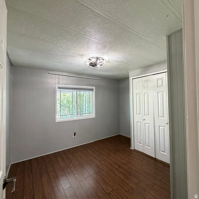 Third bedroom in the back of the property. Interior room featuring wood-finish flooring and light gray paneling