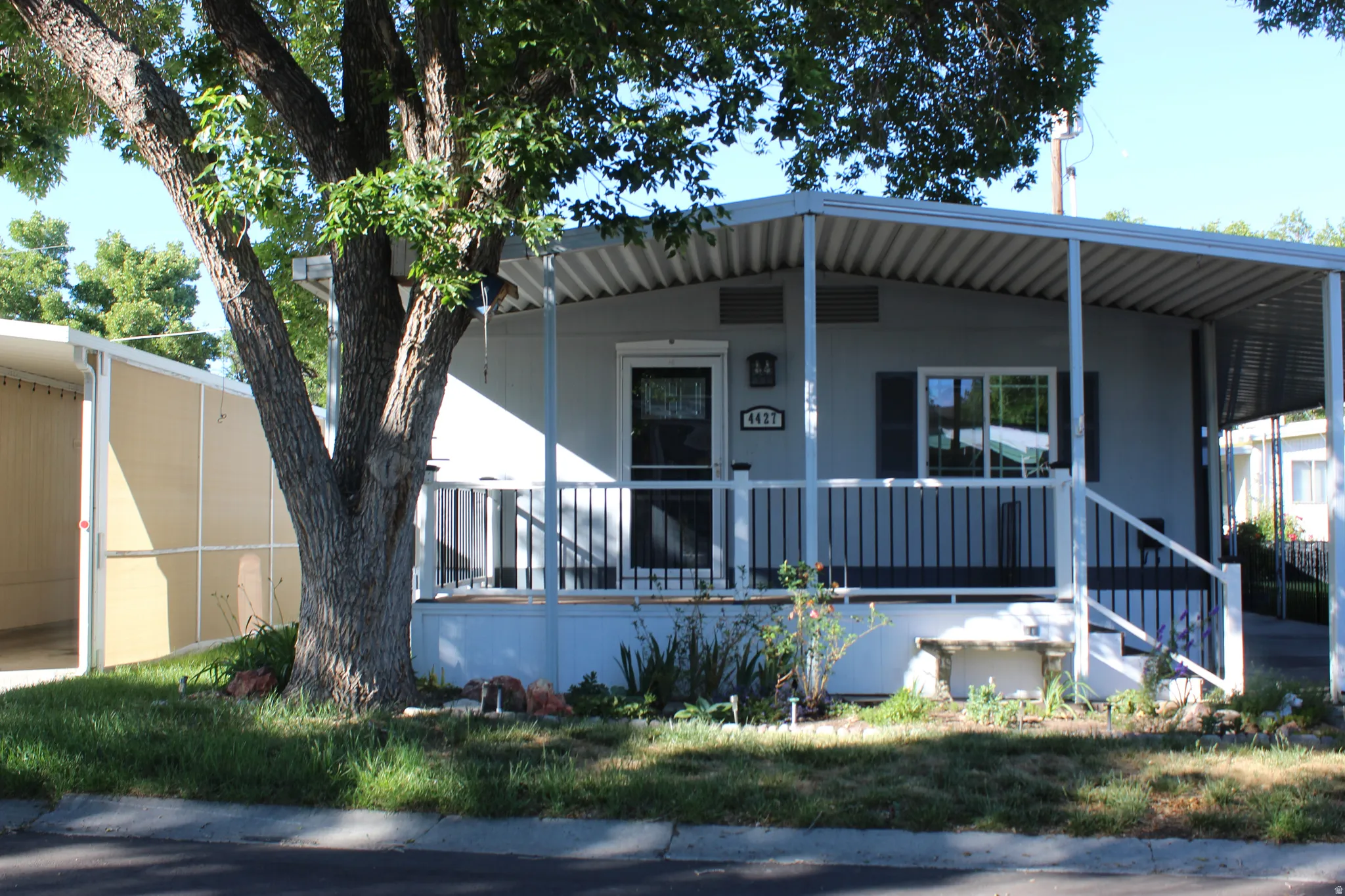 Light gray exterior featuring a covered front porch, white railings, and dark shutters