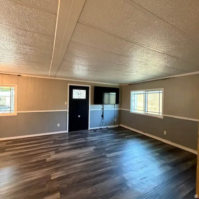 Spacious interior featuring wood-finish flooring, two-tone wall paneling, and multiple windows with horizontal grilles. view from the hallway entrance.