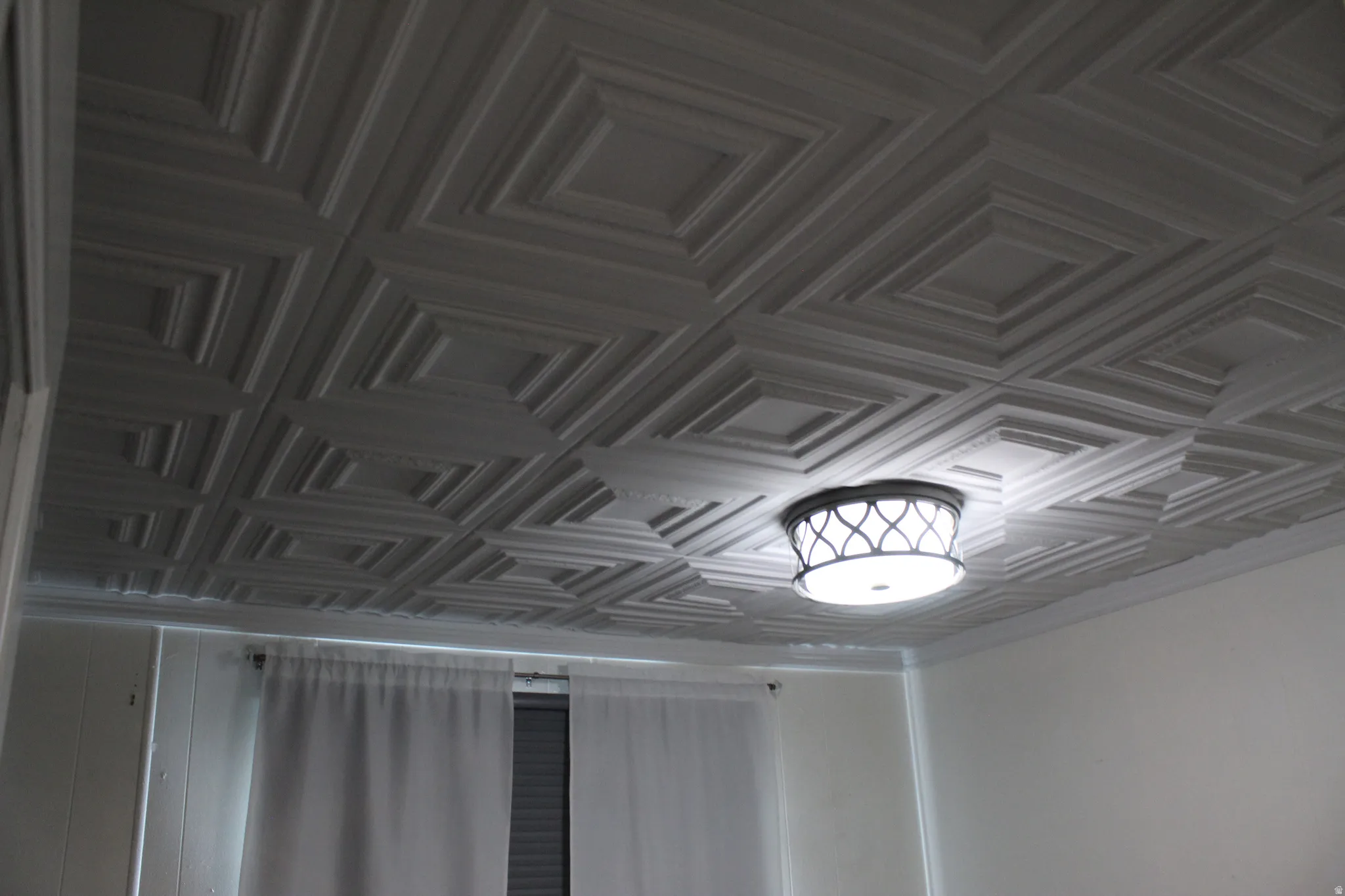 First Bedroom. Coffered ceiling with a geometric pattern and a decorative flush-mount light fixture.  first bedroom