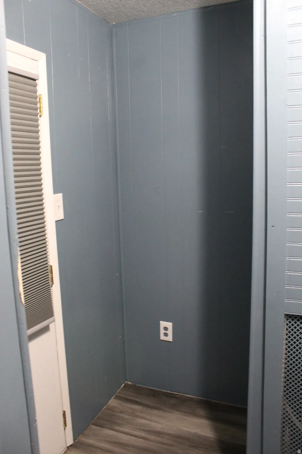 Recessed wall space featuring wood-finish flooring and a power outlet