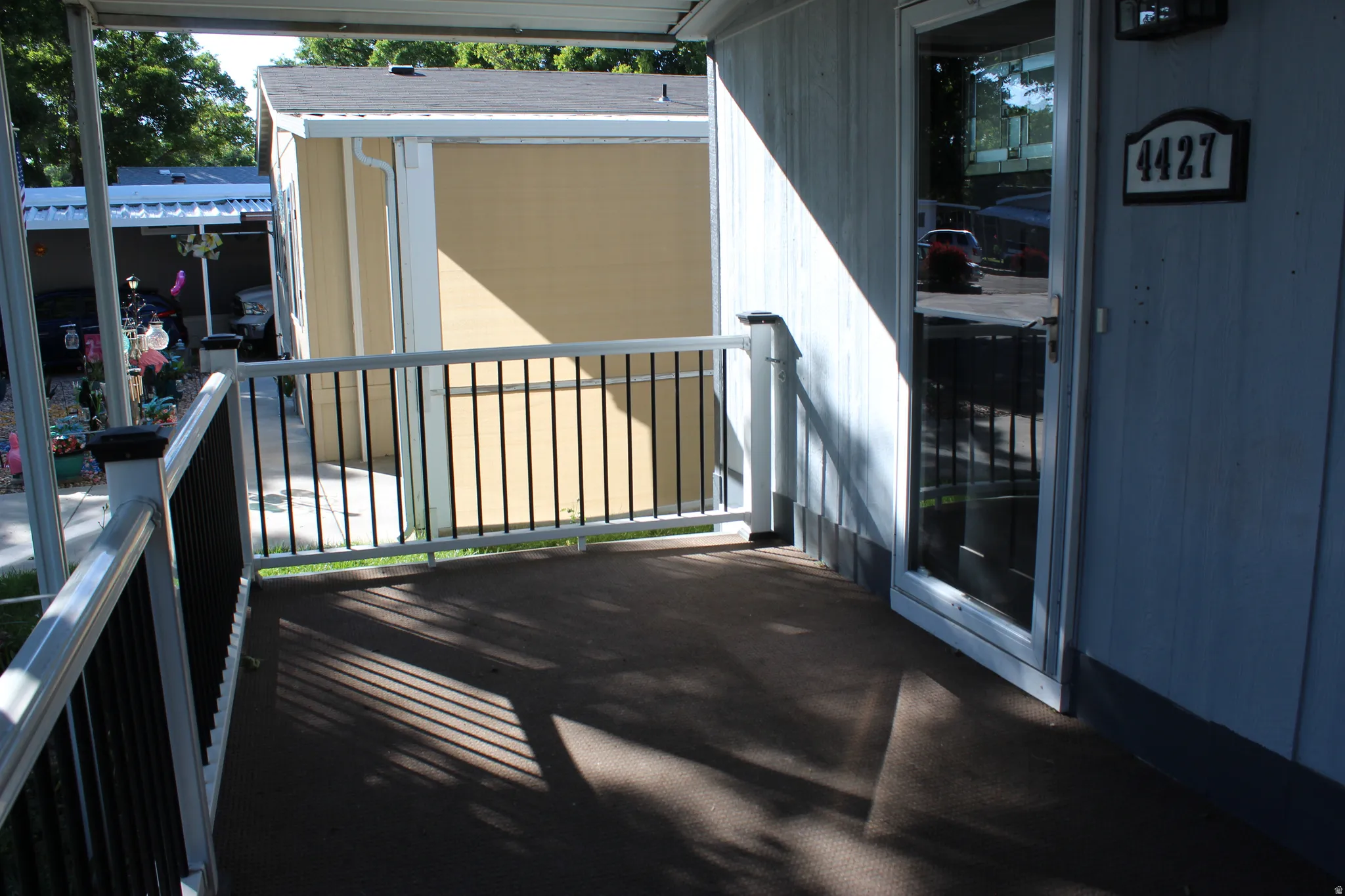 Covered porch with dark flooring, white railing with black balusters, and a storm door.  nice large porch to enjoy coffee with the sunrise or relaxing in the evening.