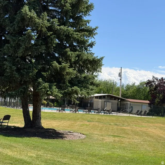 Expansive green space featuring mature trees and a fenced pool area