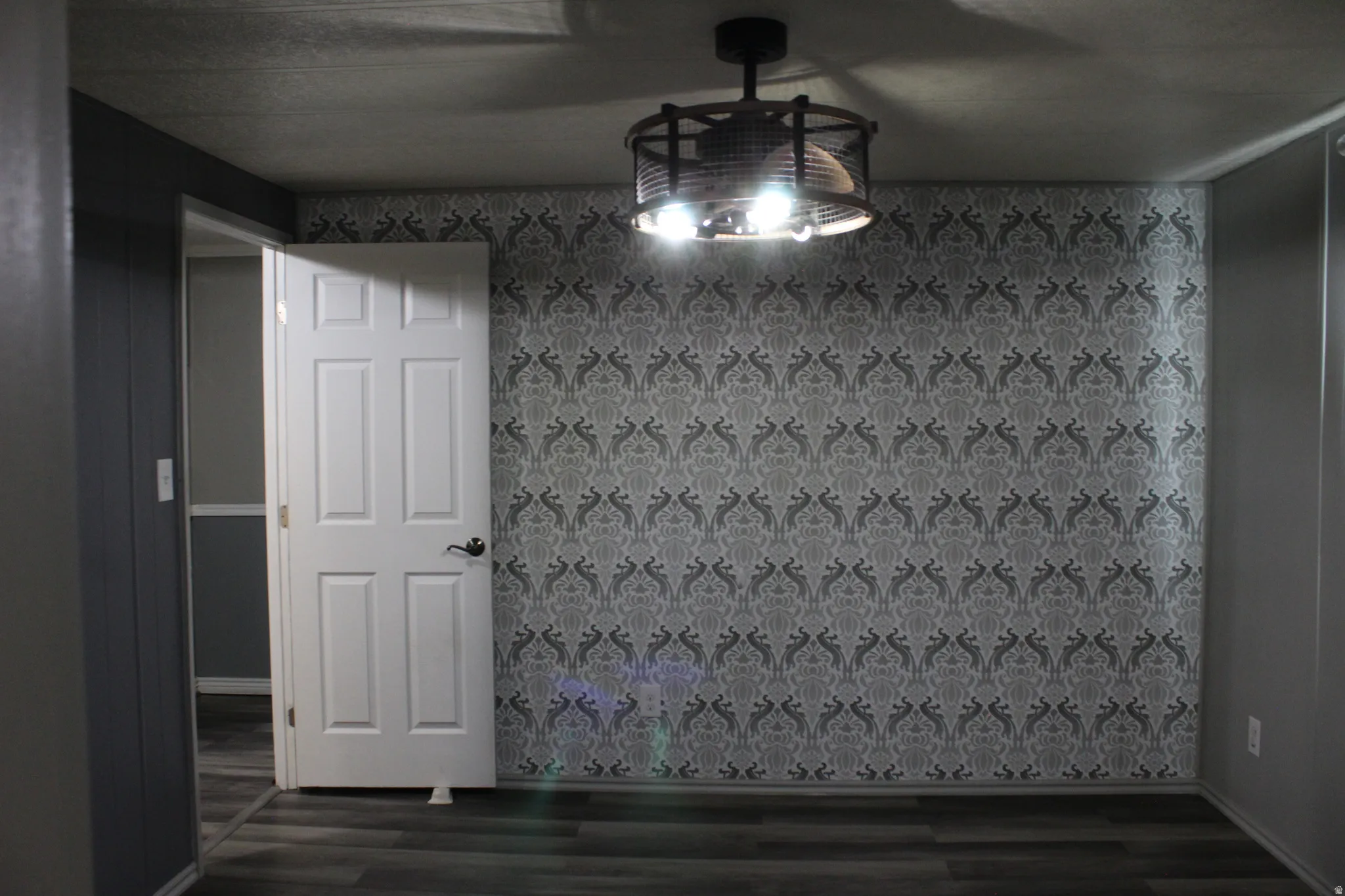 Primary Bedroom with Accent wall featuring grey patterned wallpaper, complemented by grey wood-finish flooring