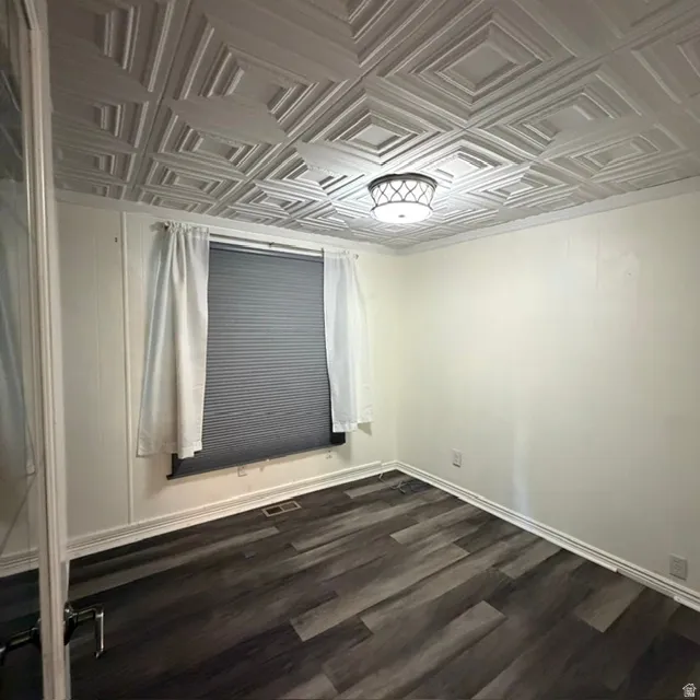 1st bedroom. Room featuring a detailed coffered ceiling, a flush-mount ceiling light fixture, and wood-finish flooring, glass door, window coverings.