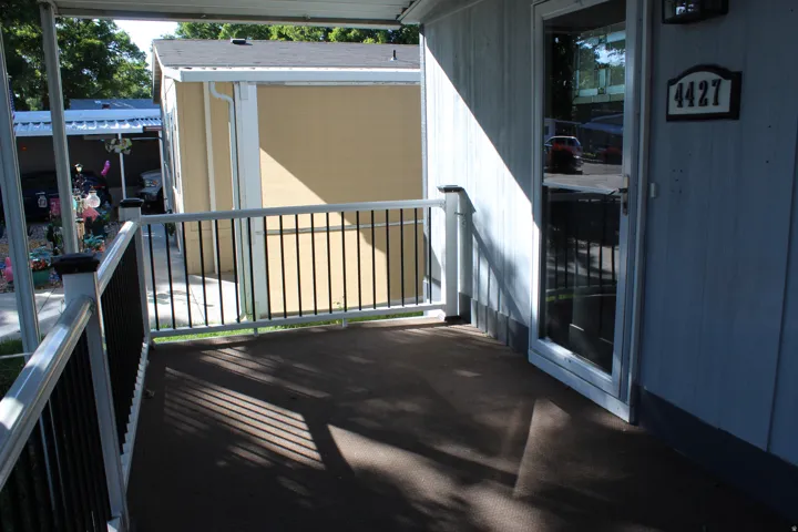 Covered porch with dark flooring, white railing with black balusters, and a storm door.  nice large porch to enjoy coffee with the sunrise or relaxing in the evening.