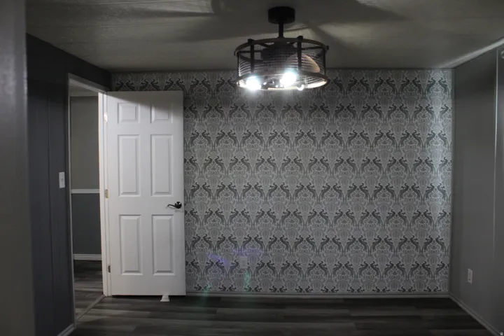 Primary Bedroom with Accent wall featuring grey patterned wallpaper, complemented by grey wood-finish flooring