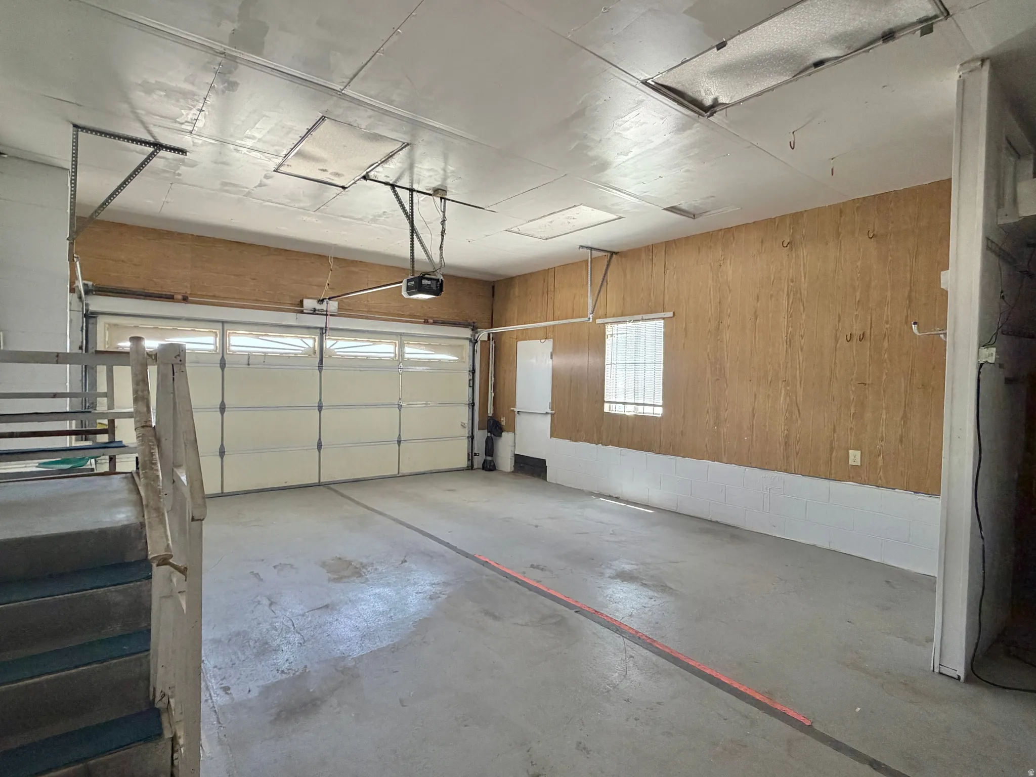 Spacious garage featuring a concrete floor, overhead door with translucent panels, and an automatic opener