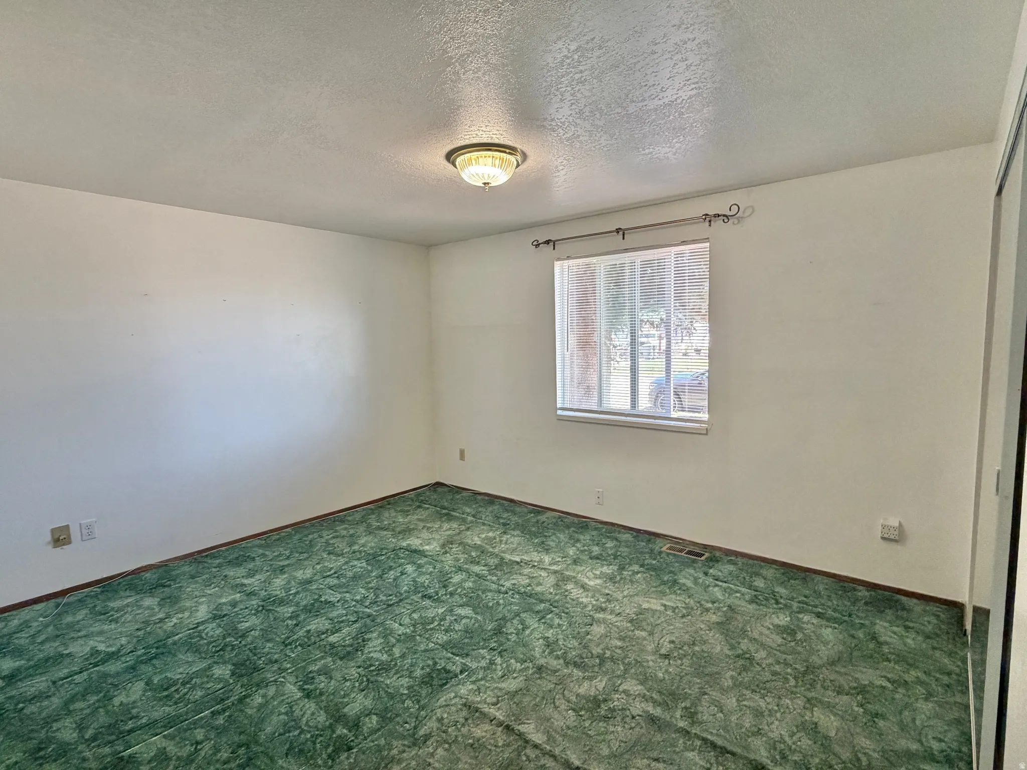 Room featuring wall-to-wall green patterned carpet and white painted walls