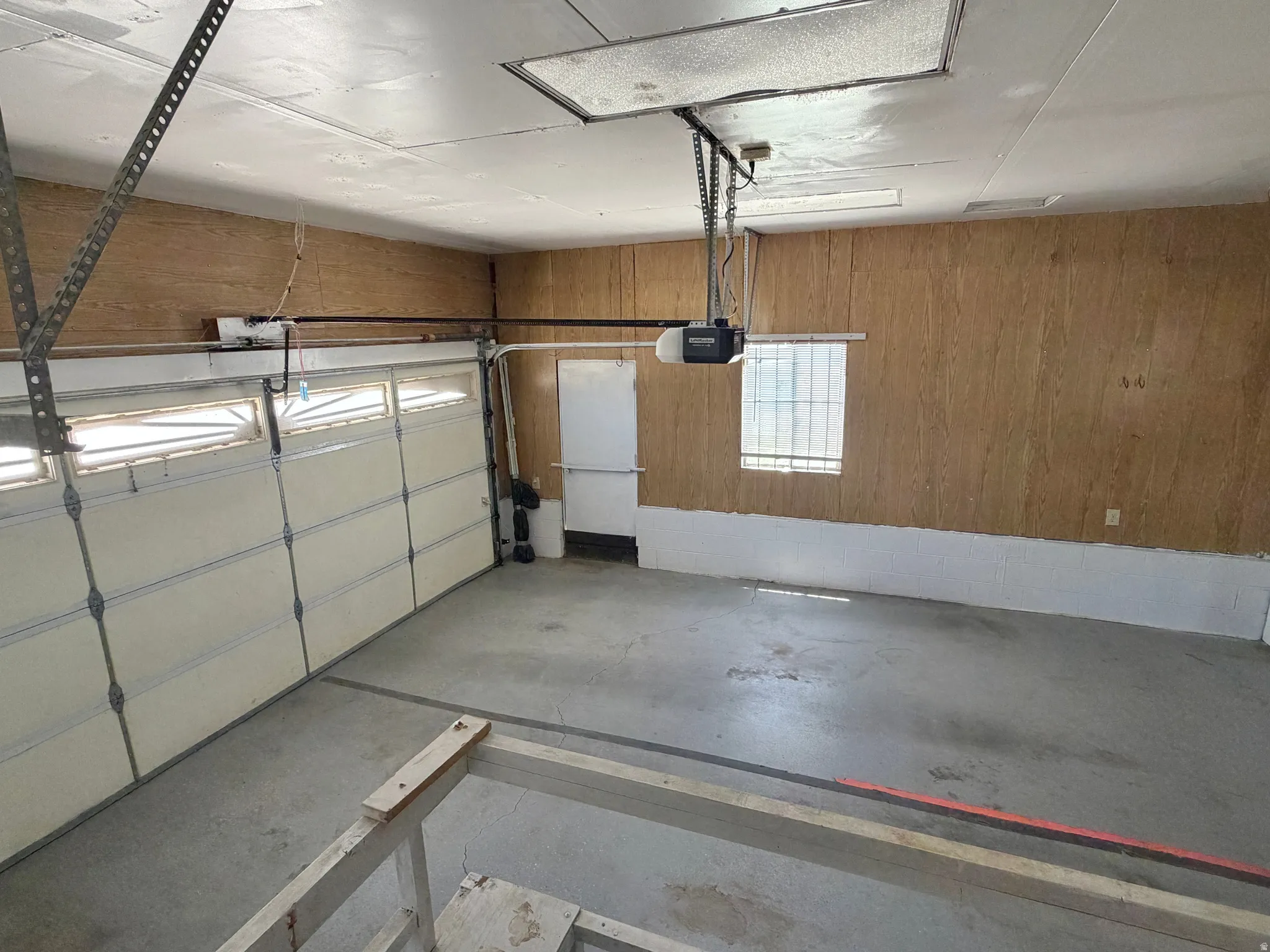 Spacious garage featuring concrete flooring, a paneled garage door with upper windows, and a garage door opener
