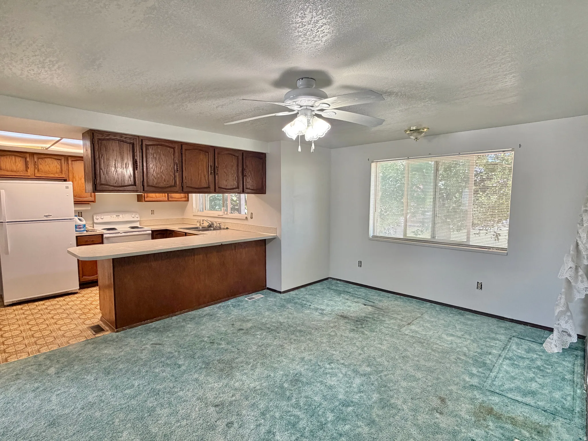 Open concept living space featuring a kitchen with wood cabinetry, a breakfast bar, and white appliances