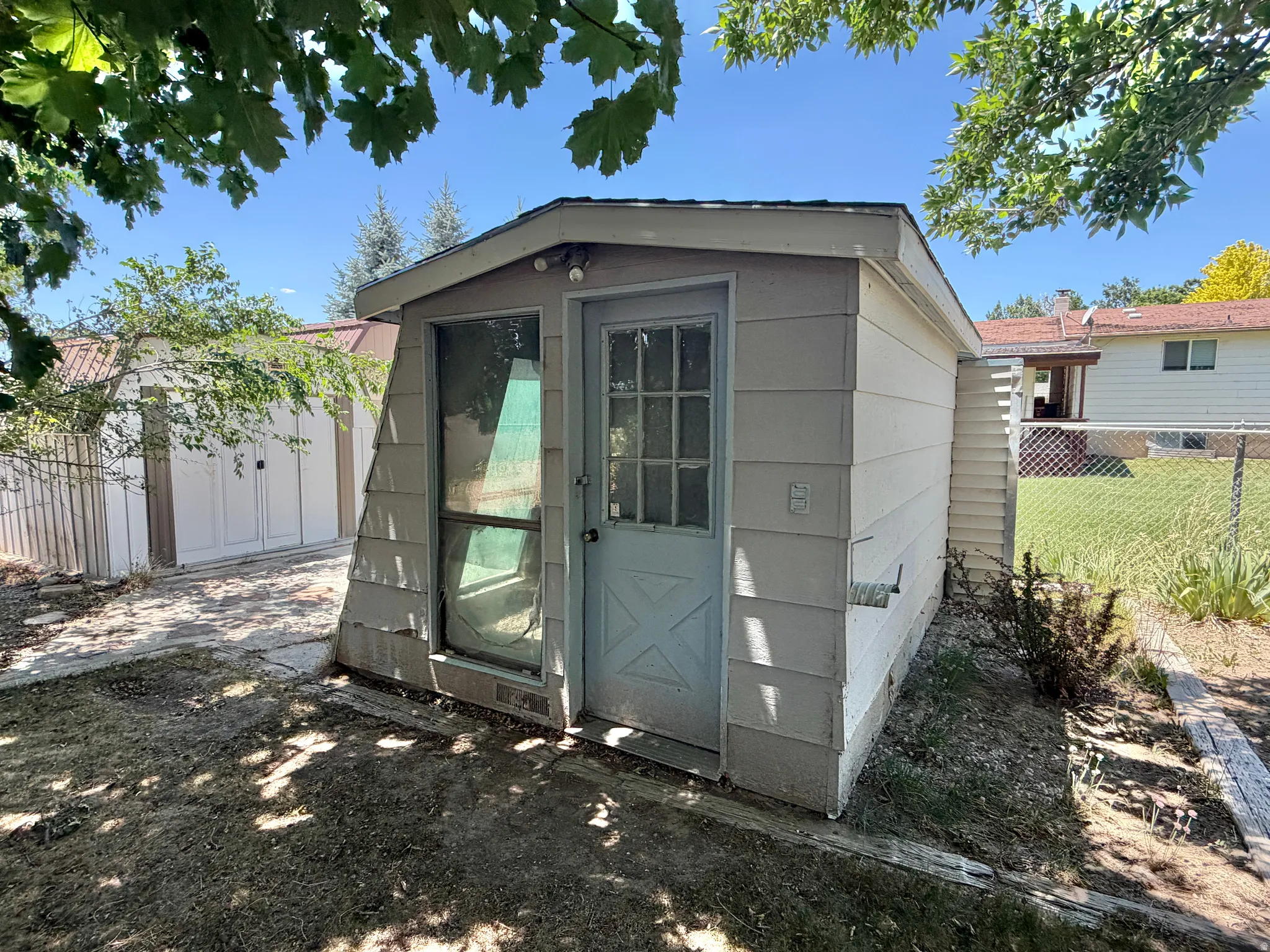 Detached shed featuring light-colored siding and a multi-pane door
