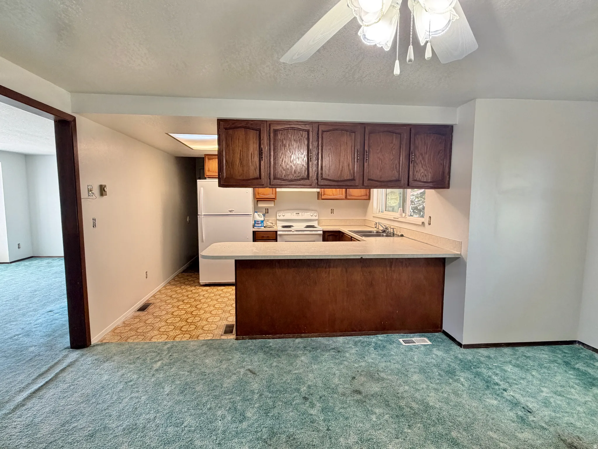 Kitchen with wood cabinetry, white appliances, and a breakfast bar