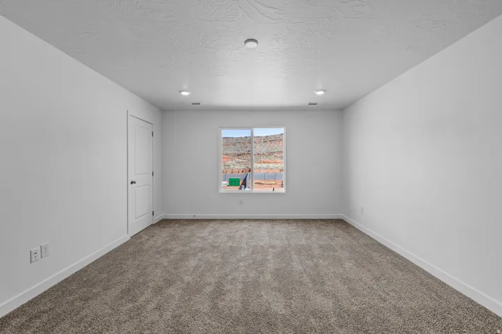 Carpeted room featuring a white interior door, a single window with mountain scenery, recessed lighting, and a neutral color palette
