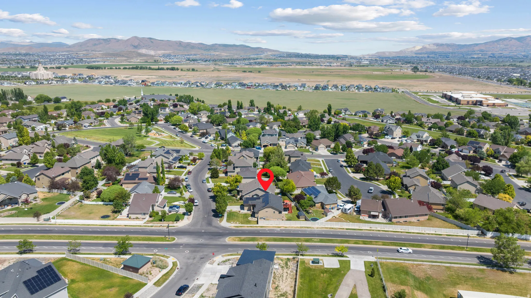 Aerial perspective showcasing a residential neighborhood with diverse architectural styles, mature landscaping, and mountain backdrops