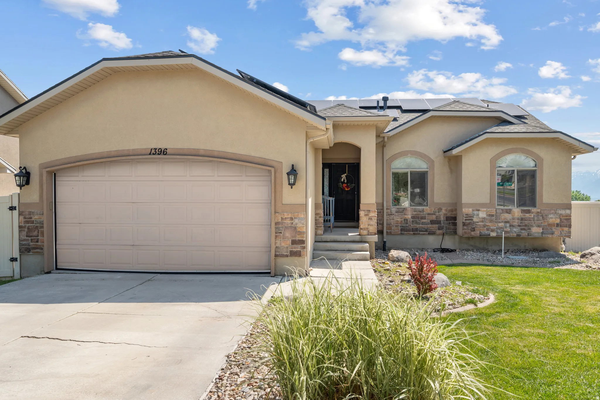 Stucco and stone facade home featuring a two-car garage, arched entry, and decorative arched windows