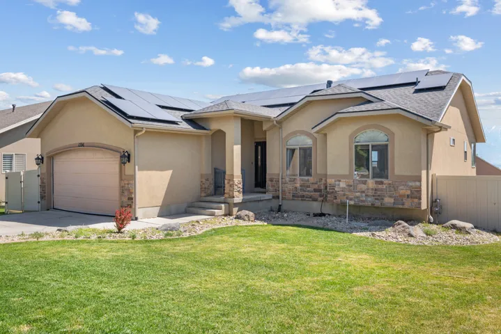 Stucco exterior with stone veneer accents and a prominent two-car garage