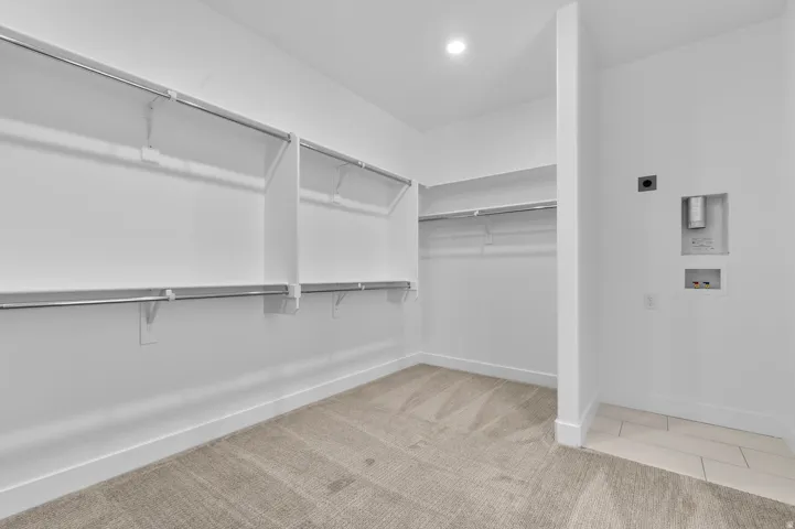 Walk-in closet featuring white walls, recessed lighting, and carpet flooring