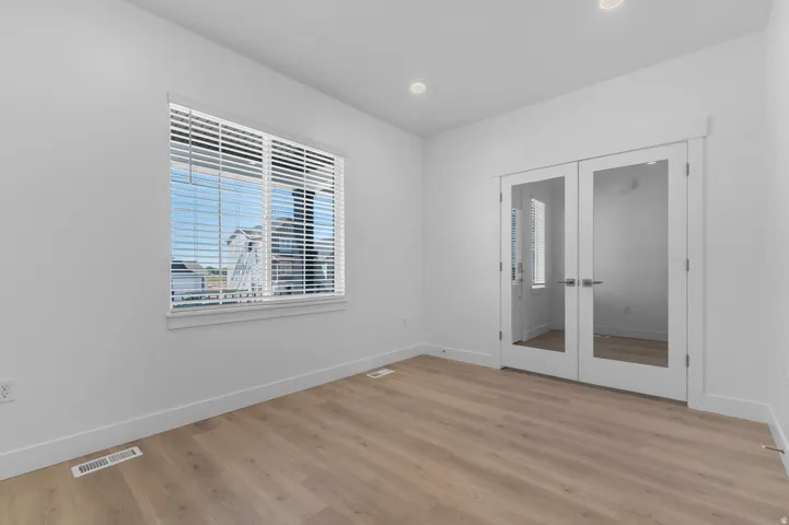 Bright room featuring wood-finish flooring, white walls, and recessed lighting