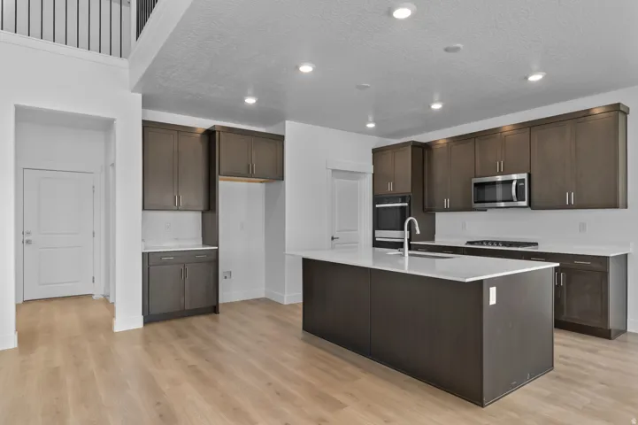 Contemporary kitchen featuring dark wood-finish cabinetry, light countertops, and stainless steel appliances