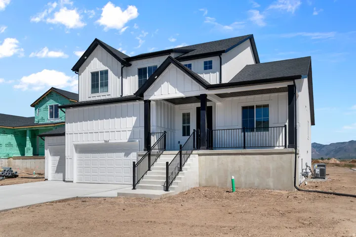 Contemporary two-story residence featuring white board and batten siding, black trim, a covered front porch with black railing, and a two-car garage