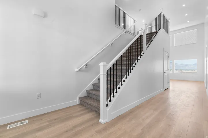 Two-story entry foyer featuring wood-finish flooring and a staircase with black iron balusters