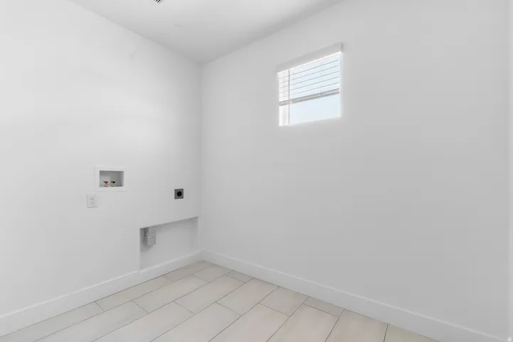 Utility room featuring white walls, baseboard trim, and light-toned tile flooring